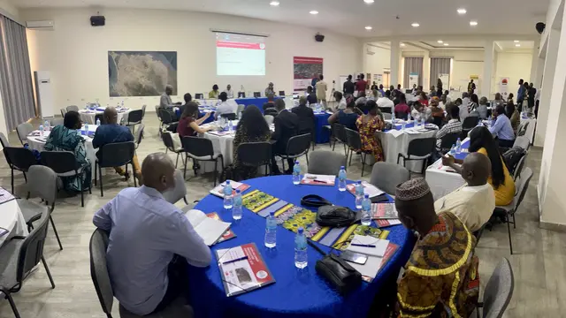 People sitting at tables facing a panel and a whiteboard behind them.