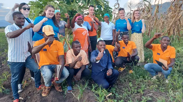 A group of young people with their hands up posing for a picture