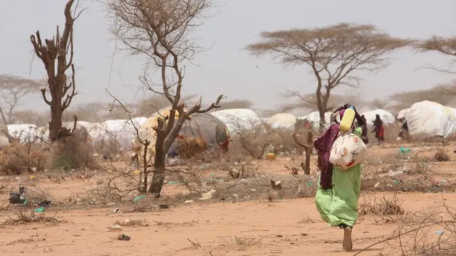 Woman carrying bags walking towards white tents