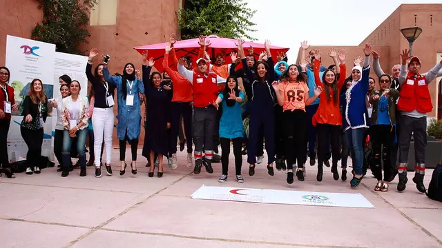 A group of people jumping in the air smiling, with their arms up.