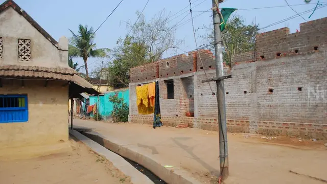 A street in a village with a house and a blue window and clothes hanging from a wire.