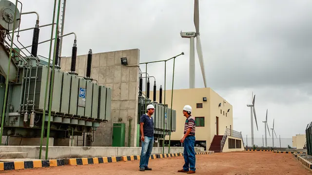 Two men standing in front of wind turbines.