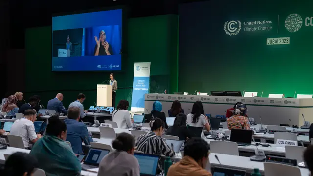 People sitting looking forward to a presentation area, with COP28 branding on the wall.