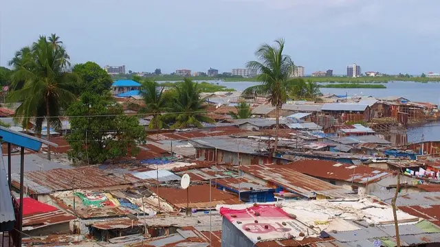 Aerial view of a densely populated slum area with numerous buildings and a river flowing through it.