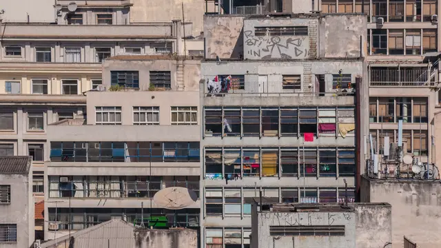 A close-up view of a building, with an abundance of windows, washing hanging from balconies and TV dishes shown outside the densely packed apartments.