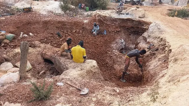Men and women dig for gold in an uncovered pit.