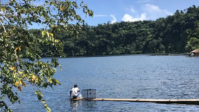 A man fishing in a large lake.