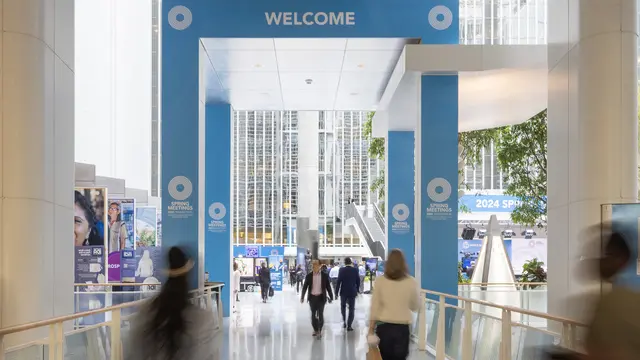 A timelapse photo that shows blurred people entering/leaving a building above which is a big sign saying 'Welcome'