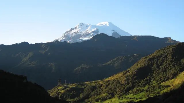 Mountainous grassland, with a glacier in the background.