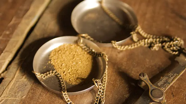 Two scale pans, one containing gold powder.
