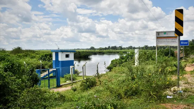 A building sits within lush vegetation under a blue sky.
