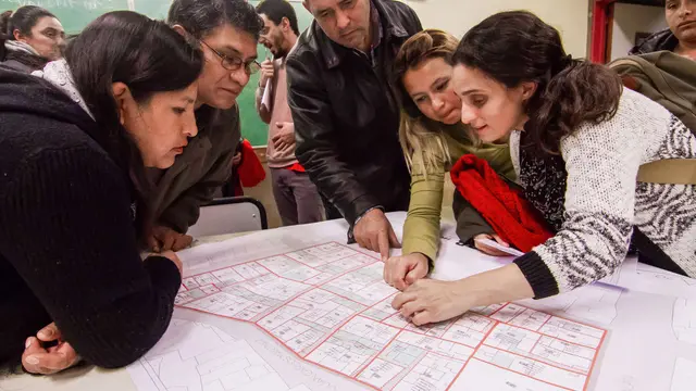 A group of people around a table, looking at plans.