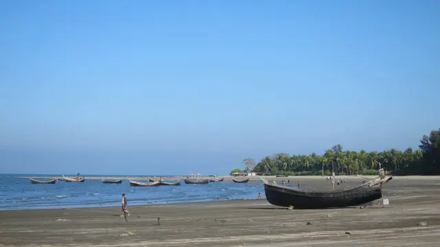 Small fishing boats just off the coast. Another boat on the beach in the foreground.