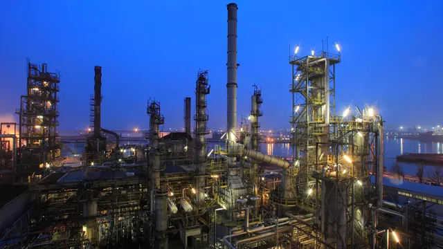 A refinery under a clear blue night sky. 