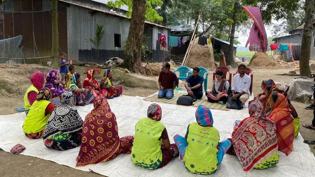 Scorecards being piloted in Bangladesh. A group of people sit in a circle and discuss.