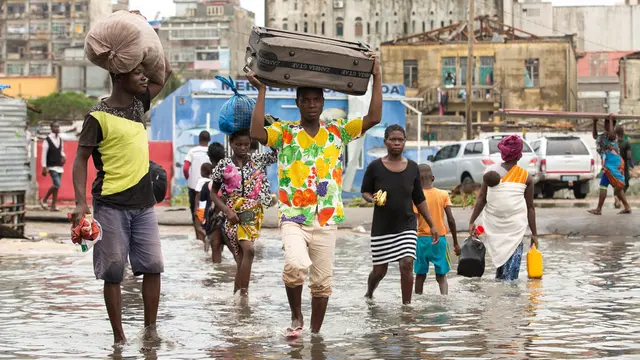 People wading through the flood waters and carrying their belongings.
