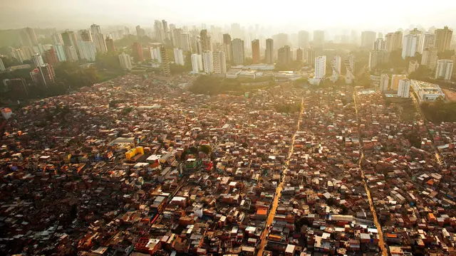 Aerial view of a cities with packed informal settlements in the foreground and skyscrapers in the background. 