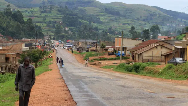 Man walking alongside a main road going through a small town in Uganda.