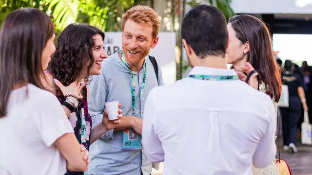 Group of people standing in a circle, talking and laughing.