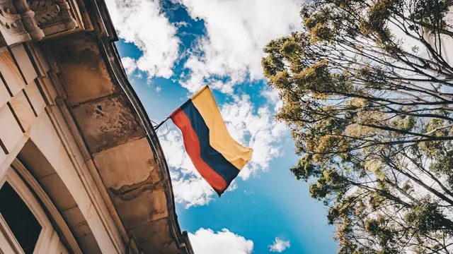 Colombian flag flying in the wind, on top of a building.