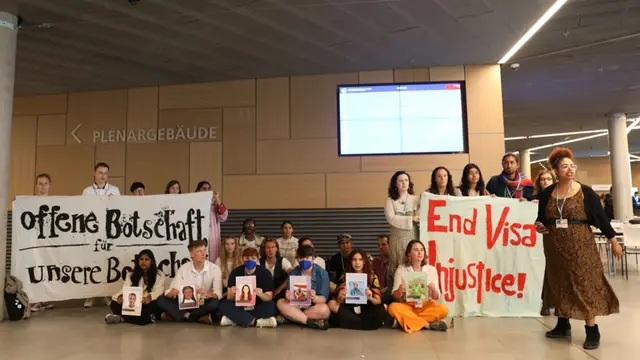Group of civil society organisation protesting in a building. They are holding signs with slogans.
