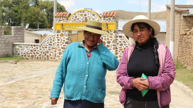 Two women from Rinconada, Jujuy wearing colorful clothing a hats, posing and looking at the camera.