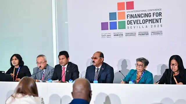 Panel of six speakers sitting down at a table. talking with microphones.