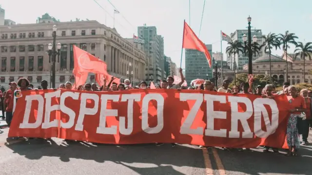 Group of people gathered for a protest in Sao Paulo, hoping a big sign that reads 'Despejo Zero'.