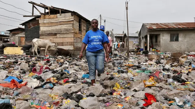 Volunteer wearing blue t-shirt walks through neighbourhood in Lagos that houses displaced people.