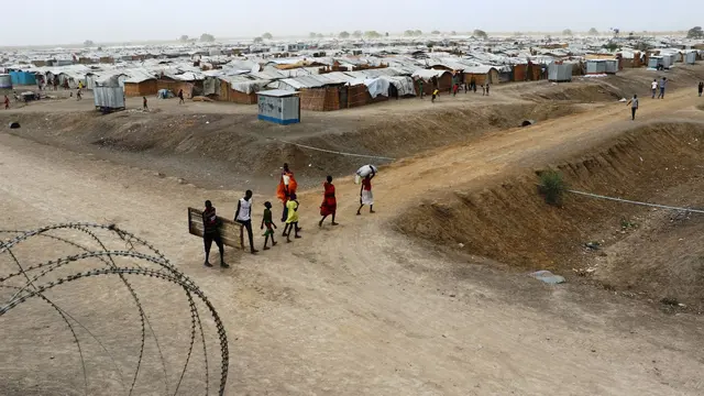 Family carrying goods and a door into a refugee camp in South Sudan.