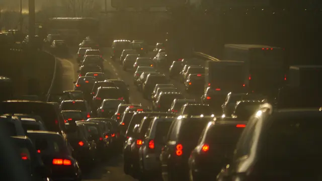 A queue of cars seen through a foggy pollution haze.