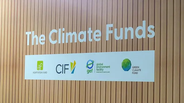 A sign at an event says "The Climate Funds" above organisation logos.