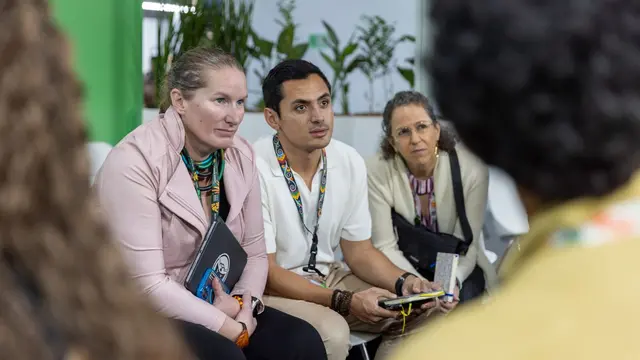 People from the Youth Group at COP30 gathered and listening to someone speak off-camera.