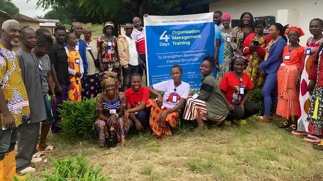 Men and women pose alongside a banner for the Twah River Beekeepers Association.