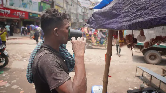 A rickshaw puller in Dhaka pauses by the roadside to drink water before continuing his route.