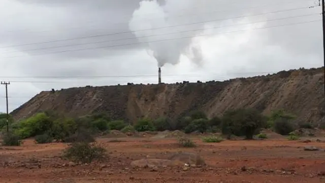 A chimney stack in the distance pours out smoke.