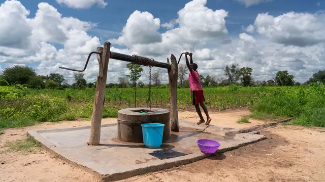 Woman pumping water using from a well in Zambia.