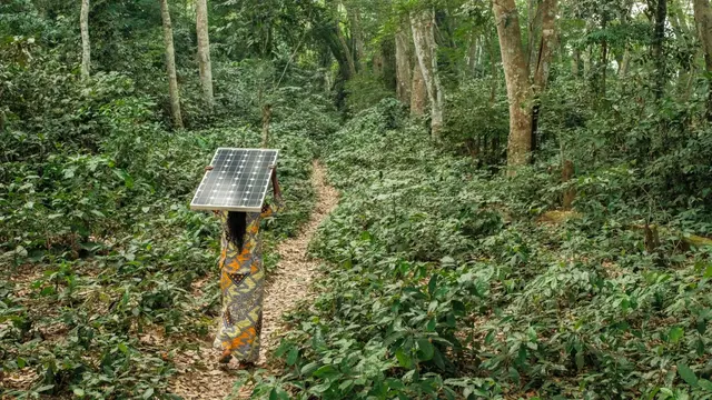 Woman carrying a solar pannel near Yangambi, DRC