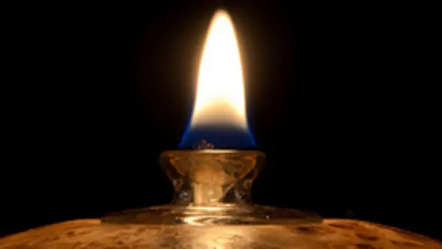 Closeup of the flame of a small oil lamp.