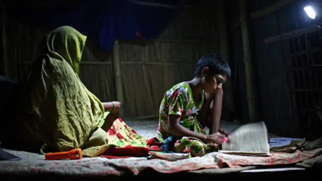A girl studies under the light of a rechargeable solar lamp