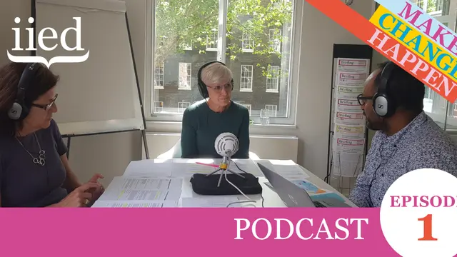 Three people talk into a microphone around the table