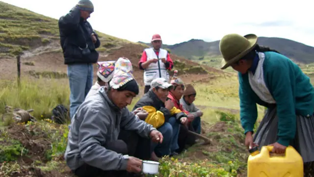 Peruvian men and women on a mountainside, pouring water on the earth
