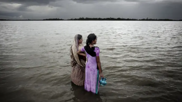 Two women look out over the rising sea water