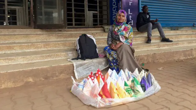 A woman sitting on steps, with colourful handkerchiefs arranged in front of her