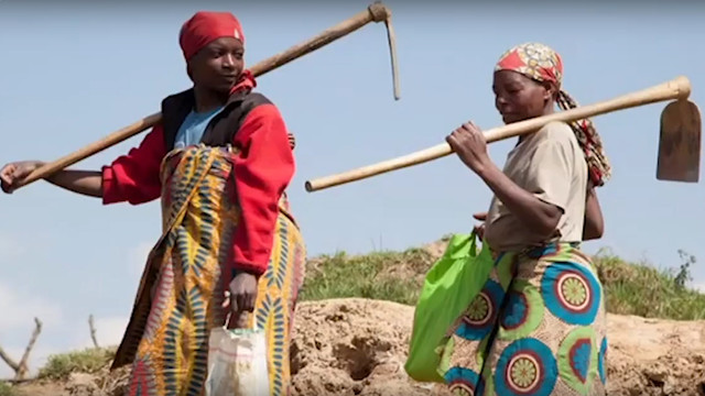 Two women carrying farming tools