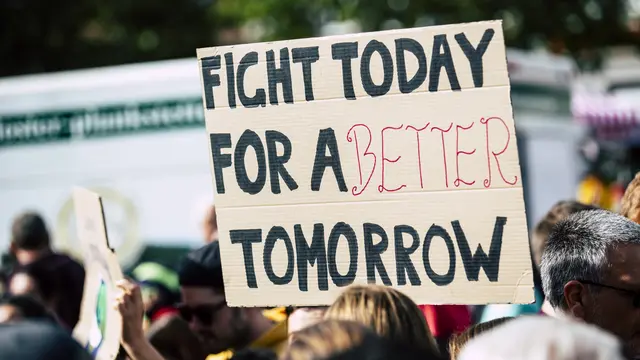 A handwritten sign is help up saying "Fight today for a better tomorrow"