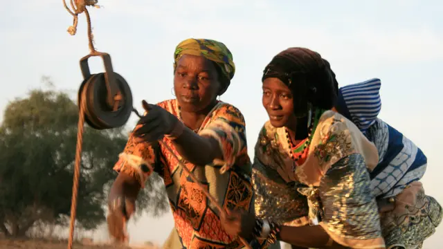 Two women draw water from a well