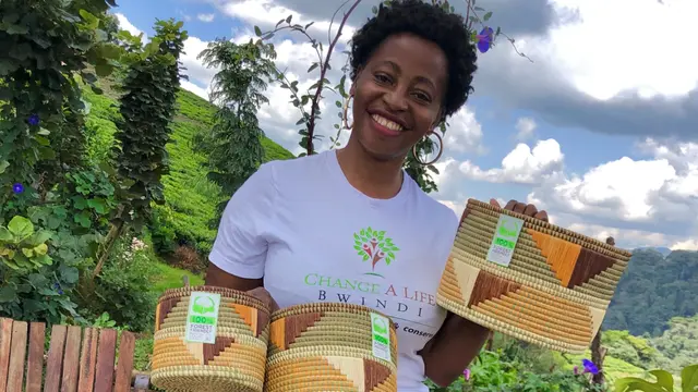 A woman holds up woven baskets
