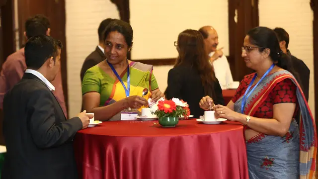 Three people stand around a table talking energetically and enthusiastically