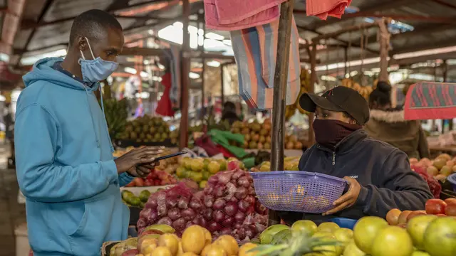 A man buying fresh fruit at a market stall.